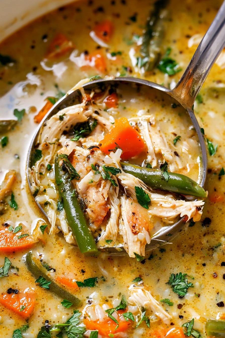 The image shows a close-up of a thick soup filled with shredded light-colored chicken pieces, bright orange carrot chunks, and green beans. The soup has a creamy, light yellow broth with specks of black pepper and herbs. Fresh green parsley leaves are scattered on top, adding a splash of vibrant color. A metal ladle is scooping some soup, showing the mixture of tender chicken, vegetables, and broth inside, all with a slightly glossy texture. The background has a white marbled texture. Photo taken with an iphone --ar 2:3 --v 7