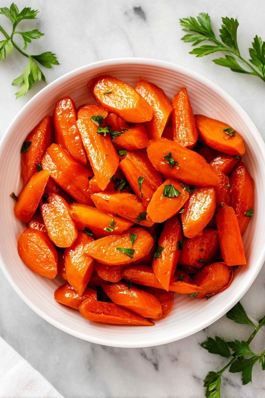 A white bowl filled with cooked carrot pieces that are cut into thick slices and small sticks, showing a shiny, slightly glazed orange surface. On top, small green parsley leaves are scattered, adding a fresh touch of color. The bowl is placed on a white marbled surface with a few fresh parsley branches nearby. The lighting is bright, highlighting the carrots' glossy texture and the contrast between the carrots and the fresh herbs. photo taken with an iphone --ar 2:3 --v 7