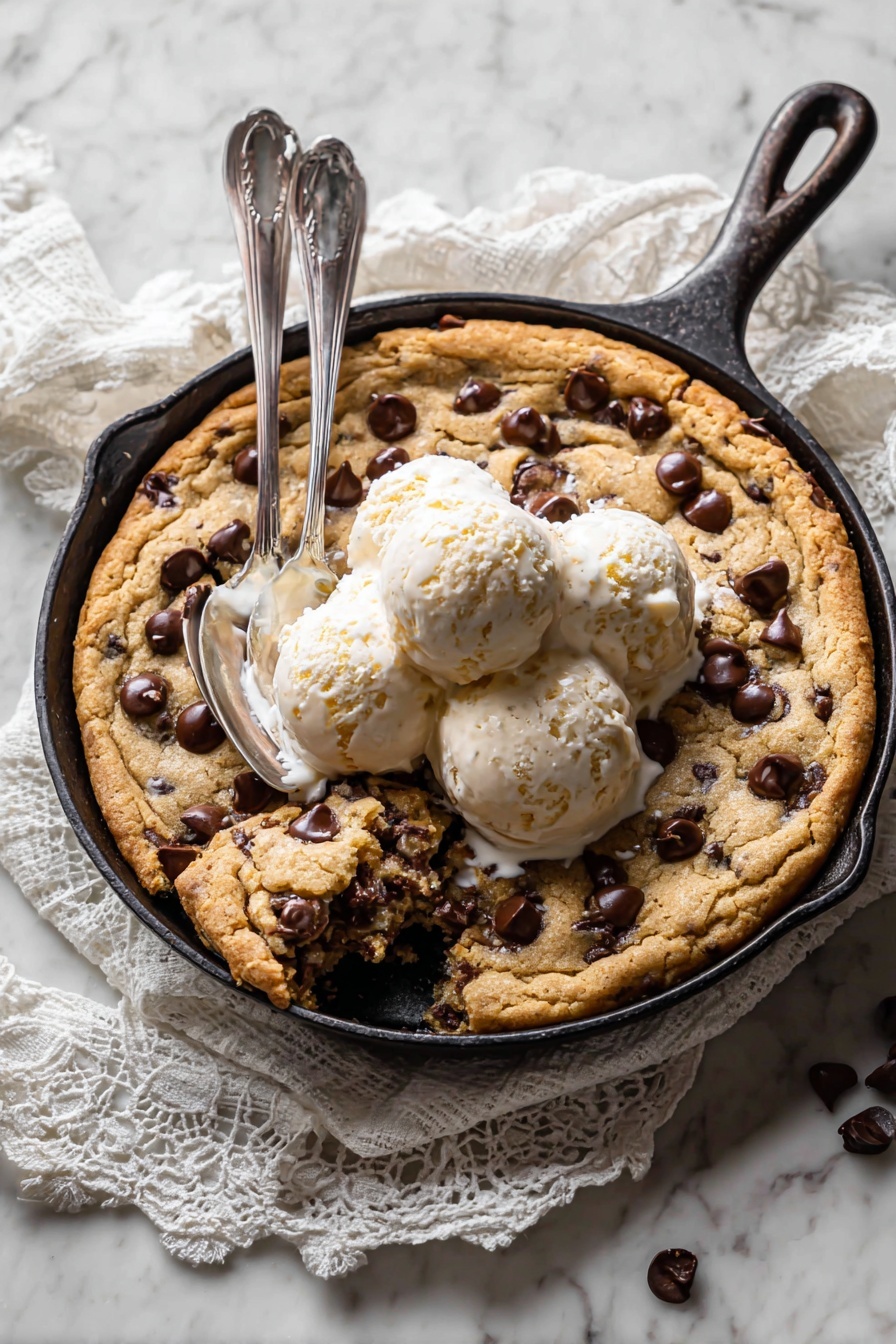 A warm, thick chocolate chip cookie is shown in a black pan with a large scoop of white vanilla ice cream melting on top, creating small pools of cream around the edges of the cookie; the cookie has a light brown, crunchy texture with dark chocolate chips spread across it and a small piece missing near the ice cream, revealing its soft inside; the ice cream's surface is smooth with small creamy ridges, and the background is a white marbled texture photo taken with an iphone --ar 2:3 --v 7